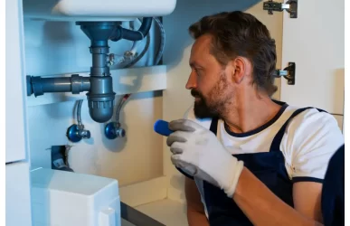 Plumber in Sydney inspecting a leaking kitchen sink before it becomes an emergency plumbing issue