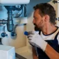 Plumber in Sydney inspecting a leaking kitchen sink before it becomes an emergency plumbing issue
